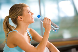 Profile of beautiful woman going to drink some water from plastic bottle after workout